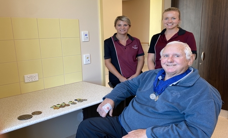 Man in wheelchair wearing Paralympic medals with two occupational therapists