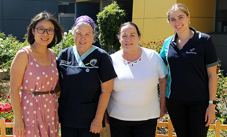 Four women stand outside hospital smiling