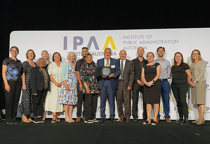 A group of men and women stand in front of a banner that reads IPAA Institute of Public Administration Australia