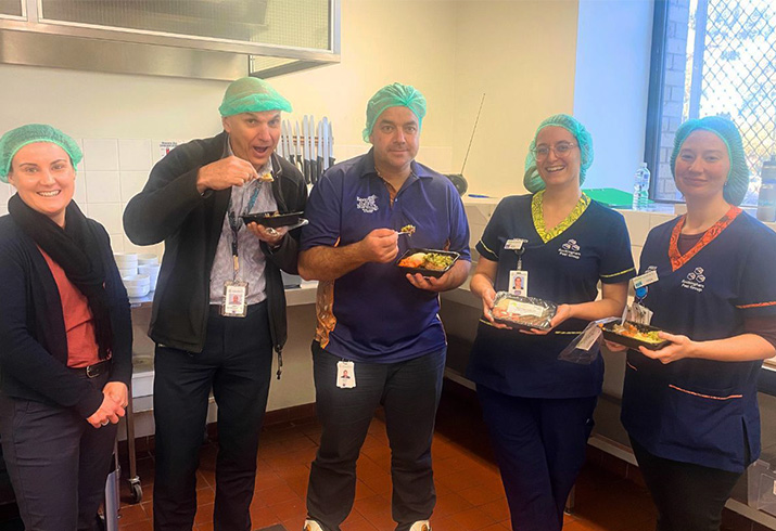 A group of health professionals stand together eating Aboriginal bush tucker